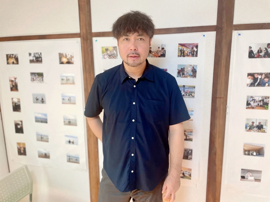 野田さんの後ろに貼られている写真は支援した若者たちと撮ったものだ