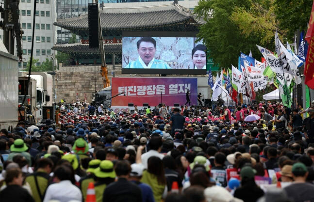 (写真：朝鮮日報日本語版) ▲親野党系社会運動団体の「全国民衆行動」や「尹錫悦（ユン・ソンニョル）政権退陣運動本部」などが28日午後、ソウル・崇礼門（通称：南大門）前で、「尹錫悦政権退陣時局大会」を開催した。写真は同日、電光板に映し出された尹錫悦大統領と金建希（キム・ゴンヒ）夫人の映像を見る参加者たち。写真＝NEWSIS