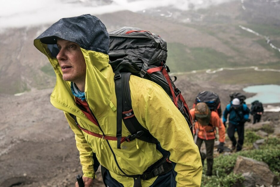 グリーンランドのセルメルソークにあるスキョルドゥンゲンの丘。雨の中、大きなバックパックを背負い、登っていく4人のハイカー。軍隊での訓練が元になったラッキングも、ちょうどこんな感じだ。(Photograph by Andy Mann)