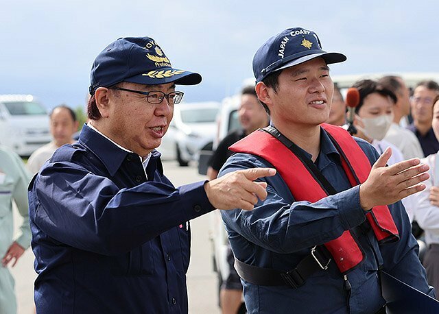 物資輸送の投下訓練は新田知事（左）が視察した＝入善町芦崎