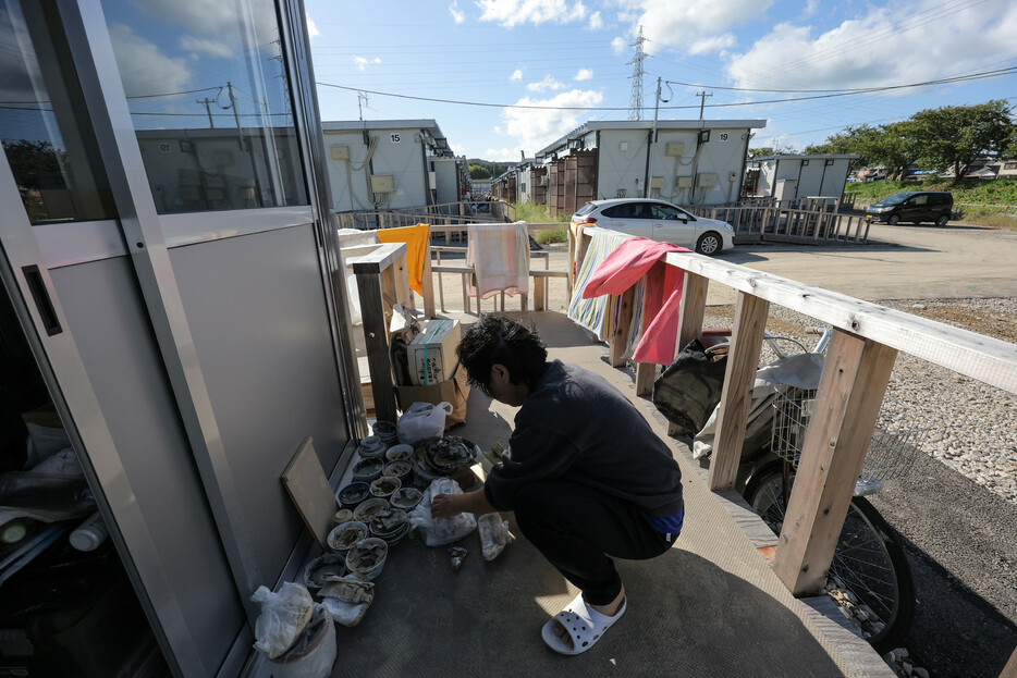 大雨による浸水被害を受けた仮設住宅で、片付けをする人＝２３日午後、石川県輪島市