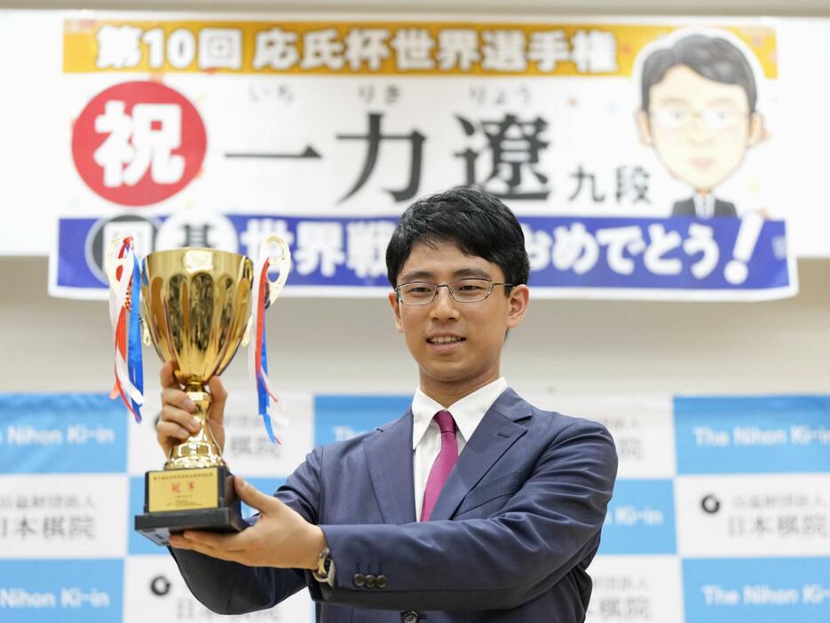 記者会見で優勝カップを手に笑顔の一力遼三冠＝9日午後、東京都千代田区の日本棋院