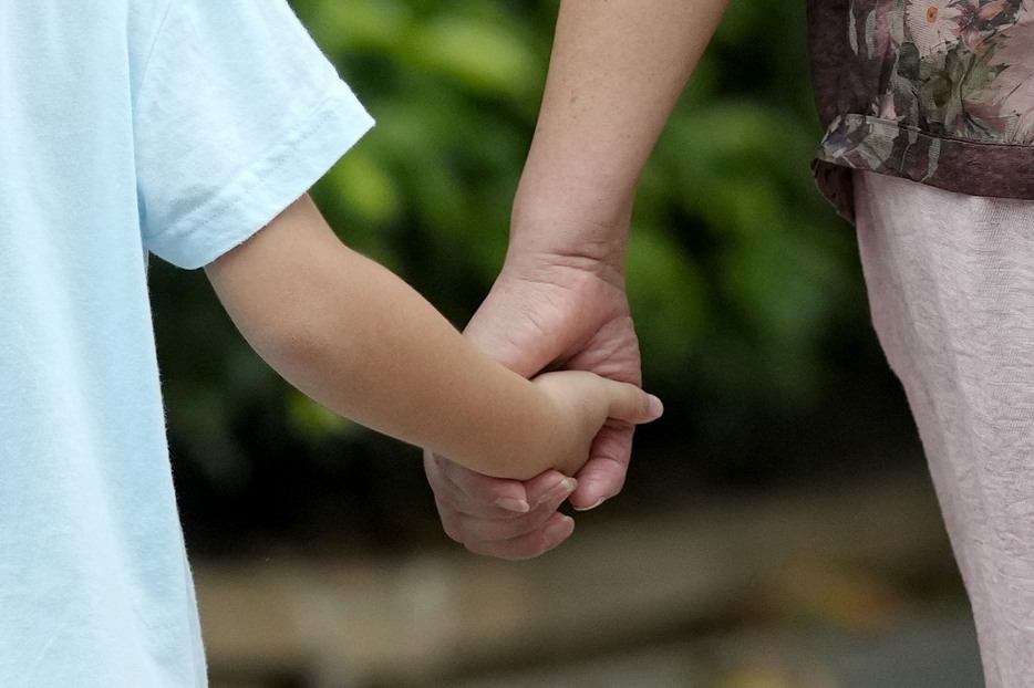 死亡した日本人学校の男子児童が男に襲われた現場付近で手をつないで歩く子どもと保護者＝20日、中国広東省深セン市（共同）