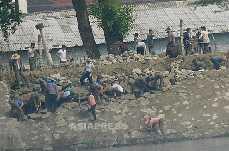 （参考写真） 手作業で鴨緑江堤防の補修作業をする北朝鮮住民たち。職場と女性同盟から動員された人々と見られる。中国側で平安北道を撮影。2021年中旬、アジアプレス