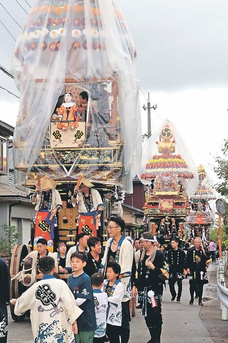 勇ましいかけ声に合わせて巡行する曳山３基＝射水市東明中町