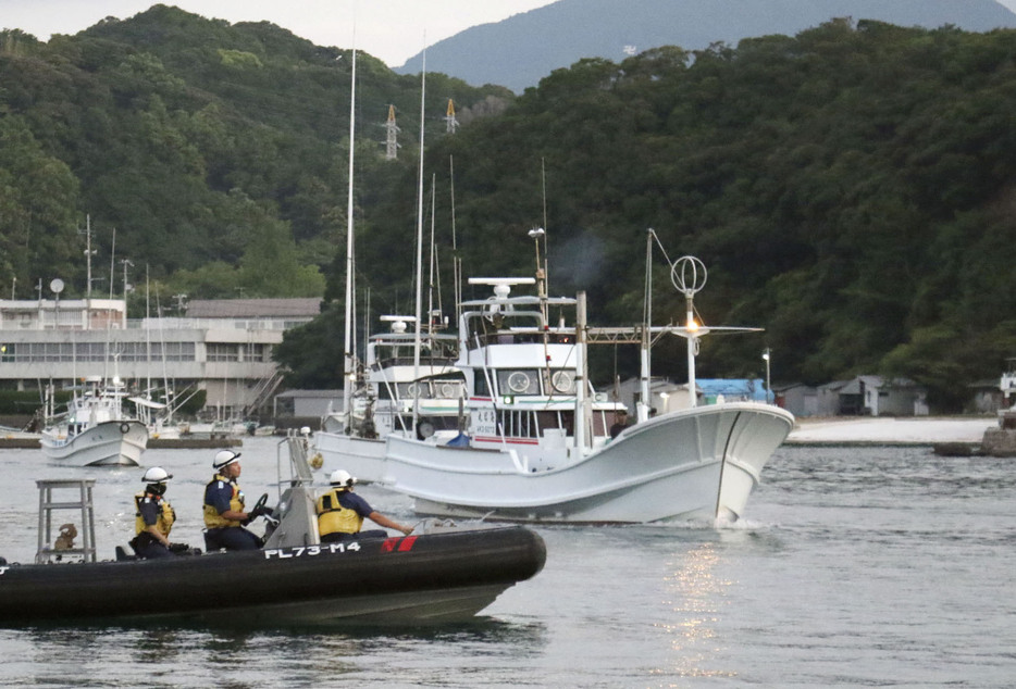 海保のゴムボート（手前）に見守られ、イルカなどの追い込み漁に向かう漁船＝5日早朝、和歌山県太地町