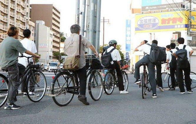 信号待ちする自転車利用者。ヘルメットの着用はまばらだ（広島市南区）