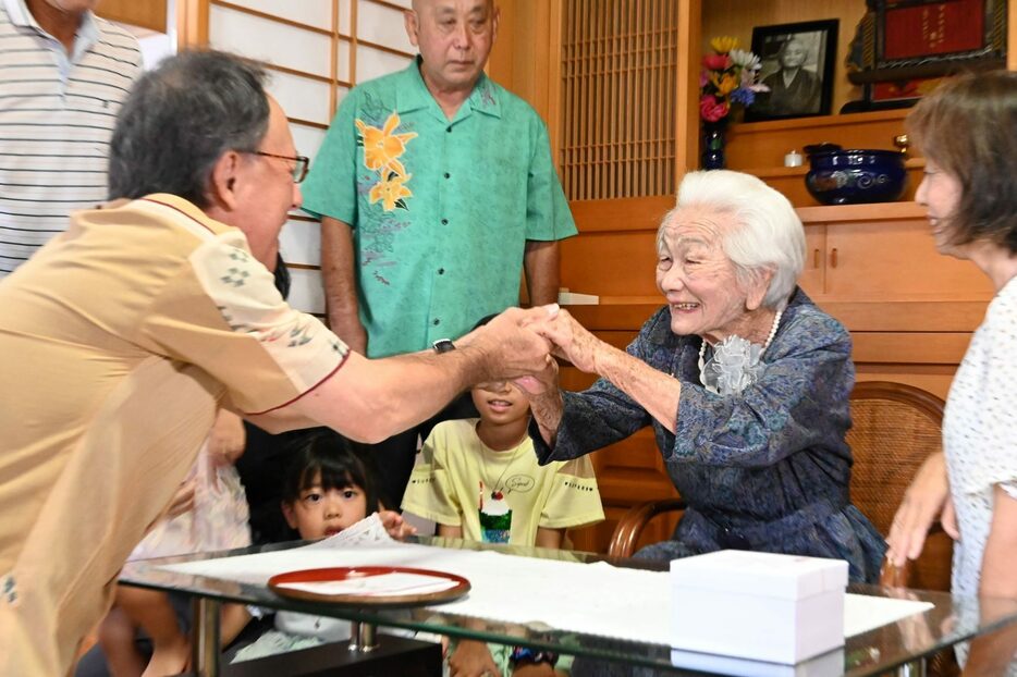 玉城デニー知事と握手を交わし、明るい笑顔を見せる大田ヨシさん＝16日、北中城村仲順