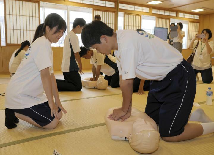 チームで協力し、胸骨圧迫などの応急手当てに挑戦する高校生