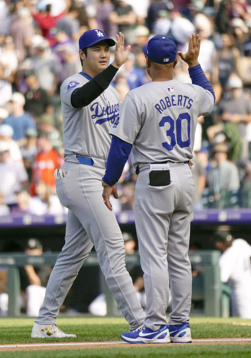 ロッキーズに勝利しロバーツ監督（右）とタッチを交わす米大リーグ、ドジャースの大谷翔平。レギュラーシーズンを終え、本塁打王と打点王の2冠を確実とした＝29日、デンバー（共同）