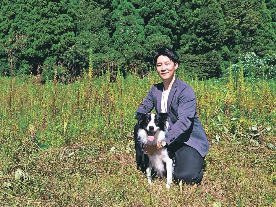 ふしきの森のオープンを進める場所で愛犬とともに笑顔を見せる中松さん＝高岡市伏木矢田新町