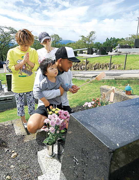 祖先が眠るお墓に近況を報告し、手を合わせる家族連れ（中山霊園）