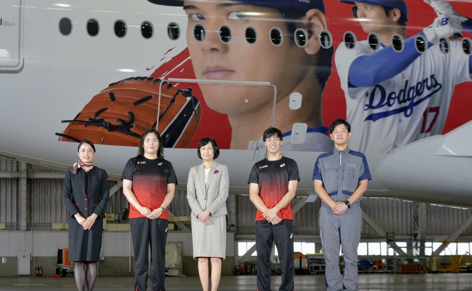 大谷翔平選手のデザインを施した日航の特別塗装機「DREAM　SHO　JET」（奥）のお披露目イベントに参加した（左2人目から右へ）陸上やり投げの北口榛花選手、鳥取三津子社長、フェンシングの加納虹輝選手＝28日午後、羽田空港