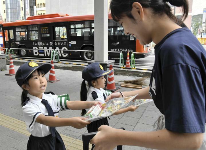 通行人に交通安全の啓発グッズを手渡す園児