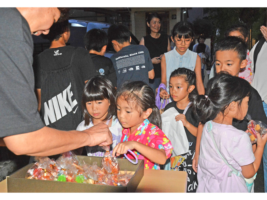 「十五夜家まわり」で住民からお菓子をもらう子どもたち＝20日、鹿児島県奄美市名瀬