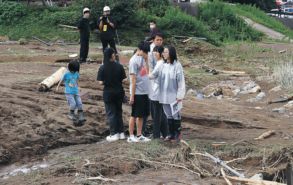 翼音さんを思い、顔を覆う同級生（中央）＝２３日午前１１時、輪島市久手川町の捜索現場