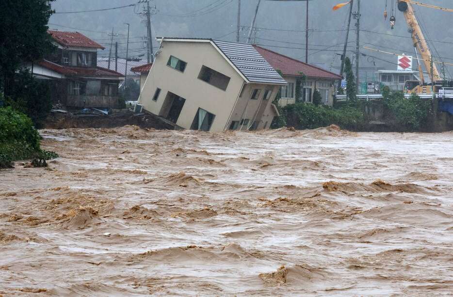 大雨の影響で、若山川の水かさが増し、傾いた家屋。持ち主の親族（55）は昨昼に家族で避難したといい、「朝まで建っていたのに。本当に言葉がでない」と話した＝22日午後、石川県珠洲市（渡辺恭晃撮影）