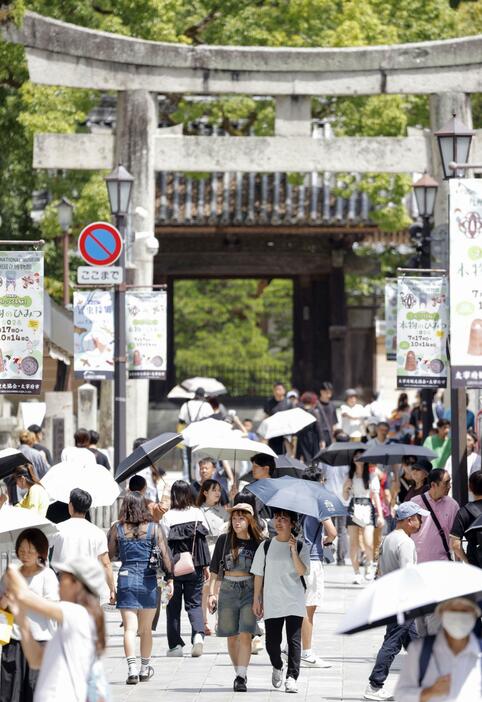 猛暑日となった福岡県太宰府市で日傘を差して歩く人たち＝8月