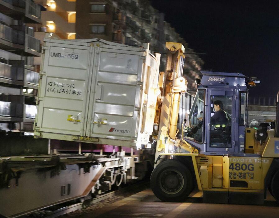 能登半島地震で発生した災害廃棄物のコンテナを貨車に積み込む作業員＝25日午後、金沢市