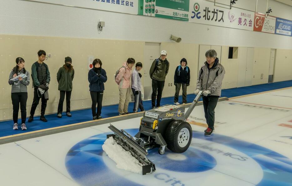 スクレイパーでアイス表面を整える作業を興味深く見る参加者たち