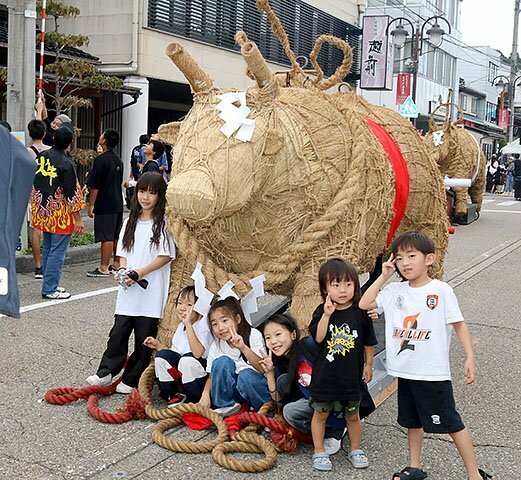 わらの牛と記念写真に納まる子どもたち