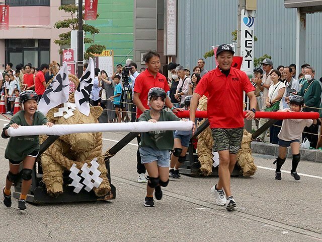 「火牛の計レース」で懸命にわら牛を引く子どもたち＝小矢部市中央町