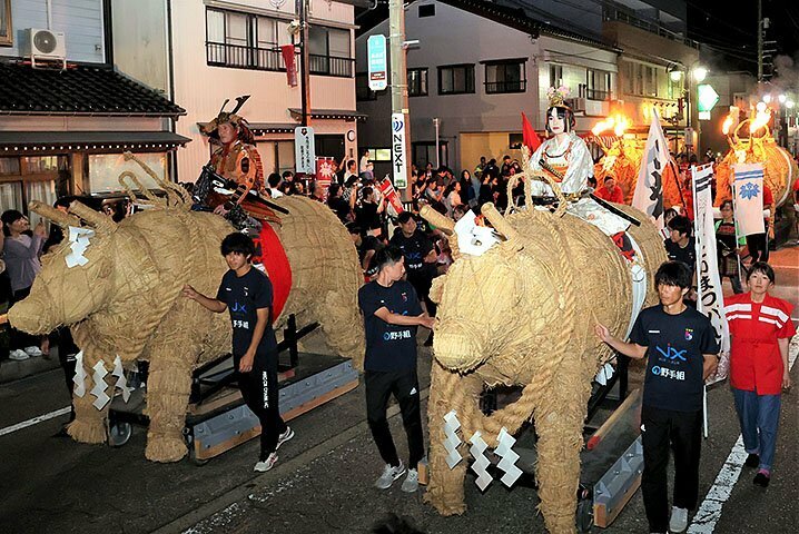 たいまつパレードで商店街を練り回るわら牛＝小矢部市中央町