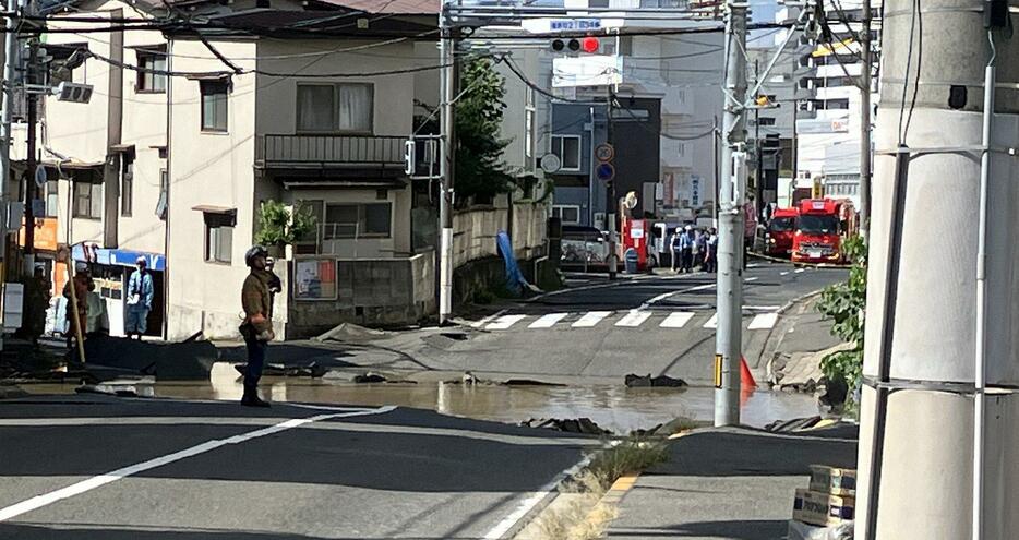 陥没し、水があふれ出た市道周辺（26日午前9時58分、広島市西区）