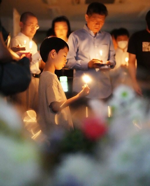 ろうそくを手に、亡くなった男児を悼む在日中国人たち＝19日、東京都新宿区