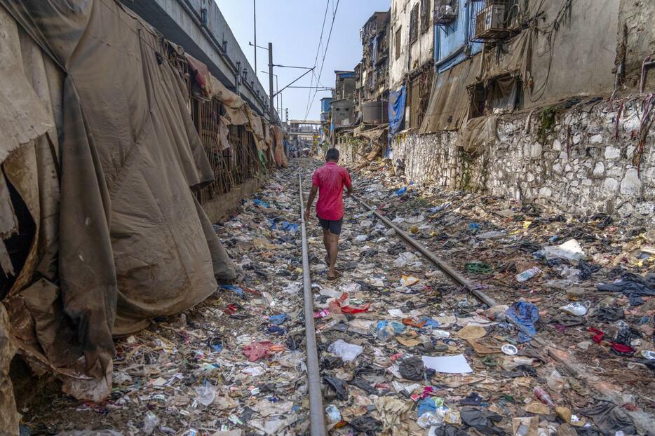 プラスチックごみなどが散乱した線路を歩く男性＝4月、インド・ムンバイ（AP＝共同）