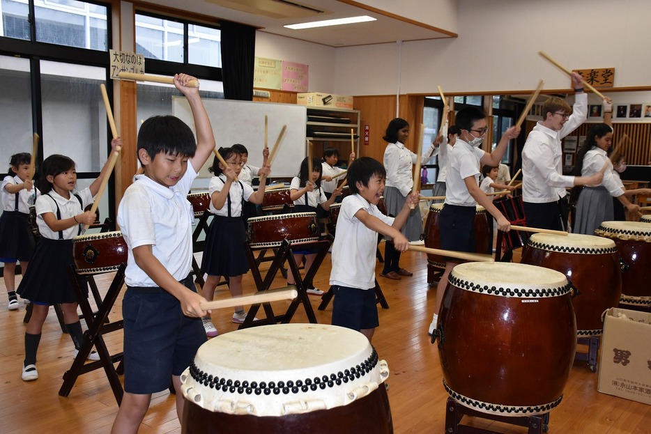 元気に和太鼓をたたく児童と留学生（厚陽小・中で）