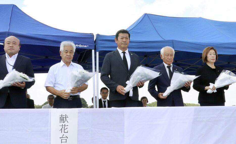 関東・東北豪雨で決壊した鬼怒川の堤防で、献花台に花を供える茨城県常総市の神達岳志市長（中央）ら＝10日午後、常総市