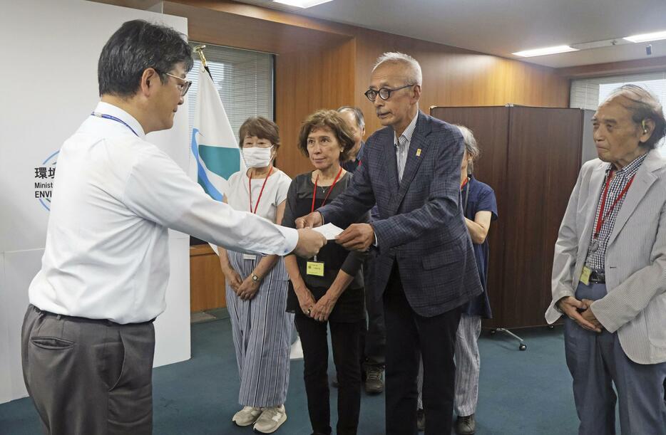 環境省で前田光哉環境保健部長（左端）に要望書を手渡す「水俣・写真家の眼」代表理事の芥川仁さん＝3日午後