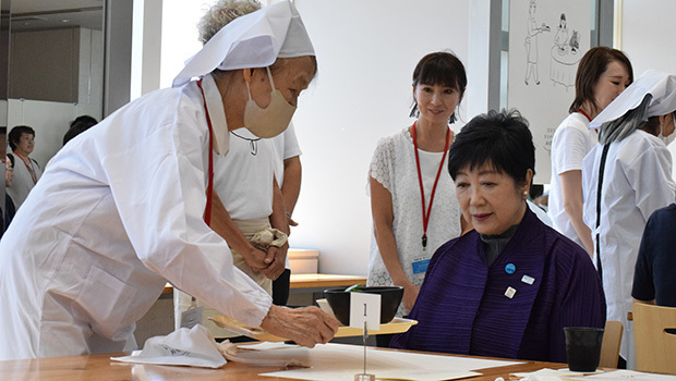 小池知事（右）に料理を運ぶ認知症のホールスタッフ