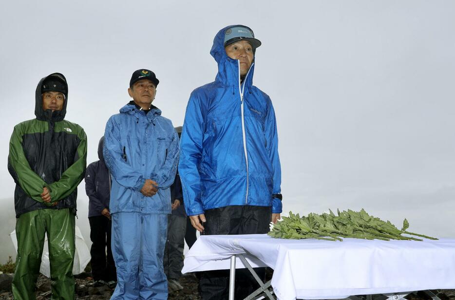 御嶽山の噴火から10年となり、活動拠点となった9合目で噴火口に向かい献花する青木幹典さん（右）＝27日午前、岐阜県下呂市