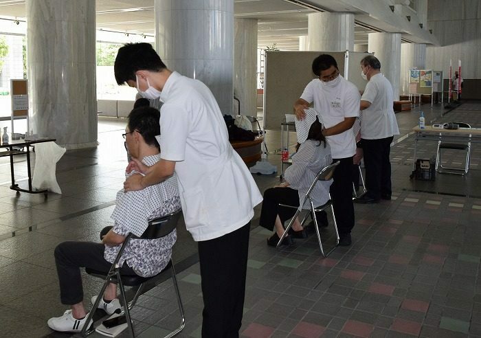 来場者にマッサージを施術する県立沖縄盲学校の生徒＝12日、県民ホール