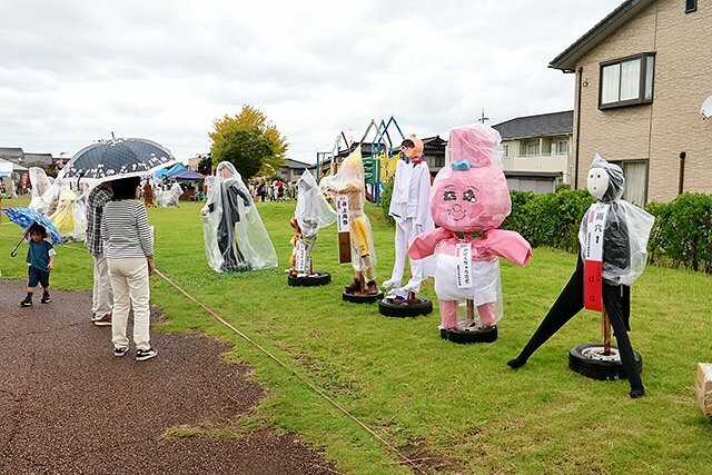 趣向を凝らしたかかしをじっくりと眺める来場者