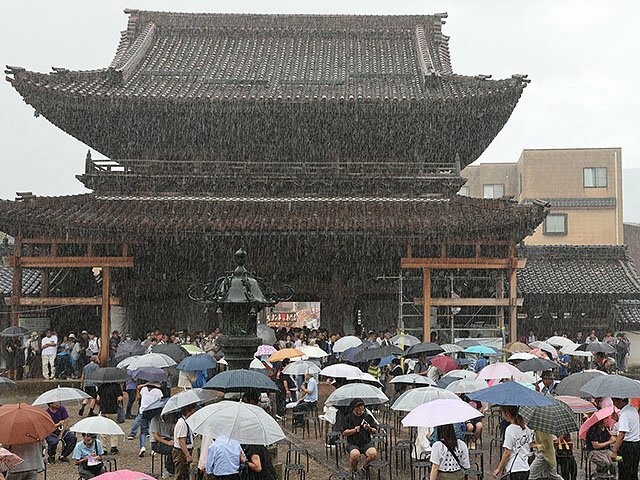 善徳寺では突然の雨にステージが中断し、大勢の人が門の下で雨宿りした