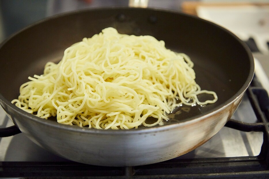 ▲ サラダ油を熱したフライパンへ麺を入れ、あまりいじらずに……