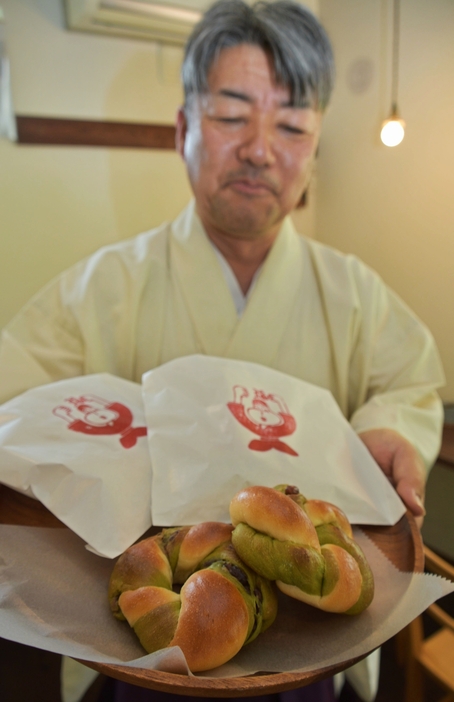 茅の輪くぐりをした人に配る「夏越パン」を手にする平林宮司