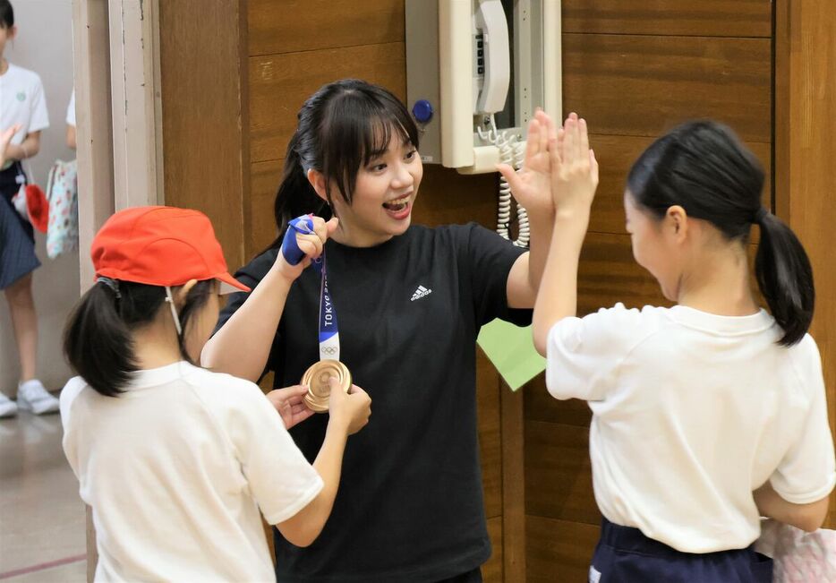 東京・墨田区の緑小学校で「特別授業」を行った村上茉愛さん（中央）。子どもたちに東京五輪の銅メダルを触れてもらいながらハイタッチでスキンシップ