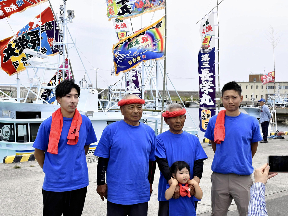 第三長栄丸を前に記念撮影する（左から）木幡さん、宮本さん、武夫さん、亮佑さん