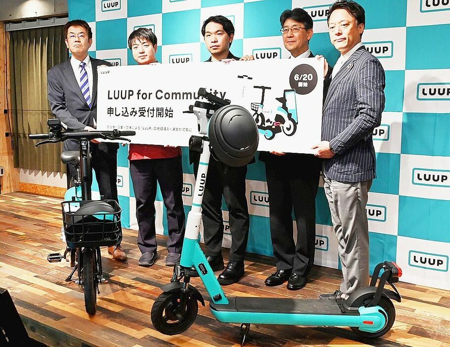 新サービスを発表する岡井社長（左から３人目）と導入自治体・企業の関係者