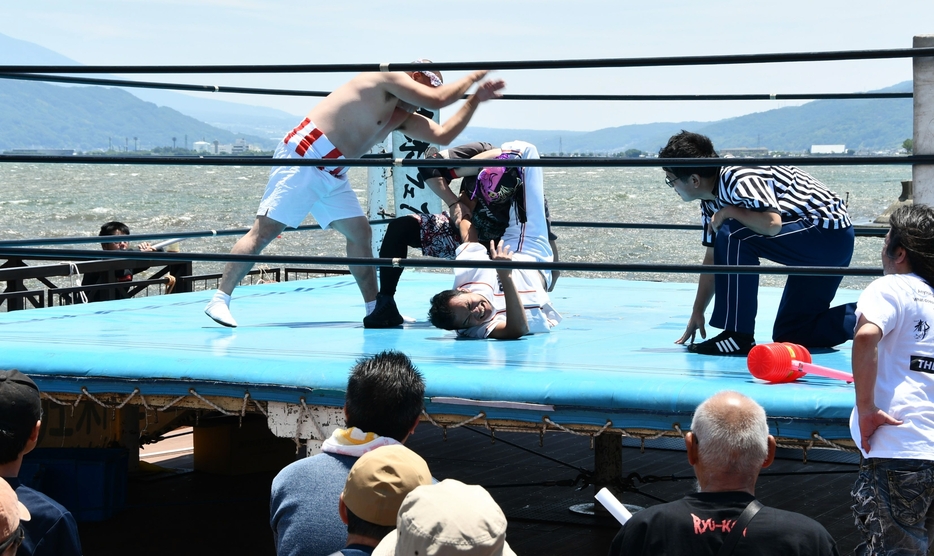 諏訪湖上のリングで対戦するレスラーら＝15日午前11時35分、岡谷市湊