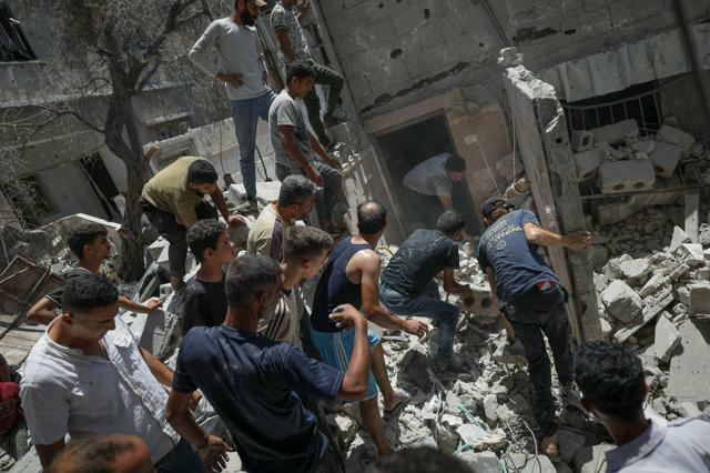 パレスチナ自治区ガザ南部のハンユニスで2024年6月25日、イスラエル軍の空爆で破壊されたがれきの中を捜索する人たち=AP