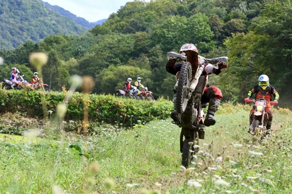 ルートを走るライダー達にウイリーをリクエスト。それに応えてくれるライダー達。ここは競争区間ではなく移動路なので、レース中なのに和やかな感じなのが、他には見られない特徴です。　Photo：宮崎大吾　2018年度大会の模様