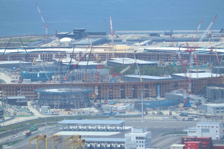 ［写真］リング内は地面が見える割合が減少。リング手前の建屋では屋根の工事も進行