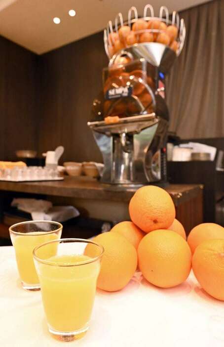 出来たてのオレンジジュース。後ろのジュースマシンで１杯ずつ搾られる＝東京都新宿区のリーガロイヤルホテル東京（酒巻俊介撮影）