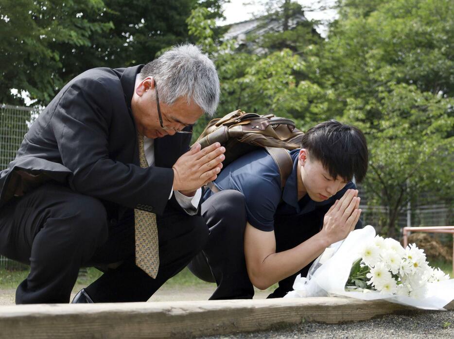 松本サリン事件で犠牲者が出た寮跡地の公園で、献花し手を合わせる映画監督のさかはらあつしさん（左）ら＝25日午後、長野県松本市