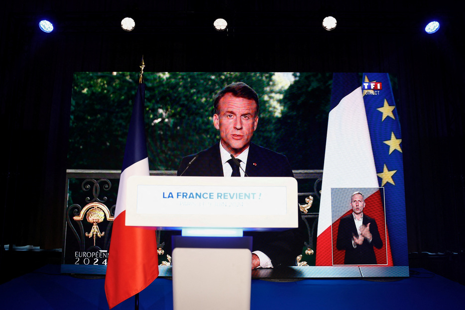 　６月９日、フランスのマクロン大統領は、国民議会（下院）の解散総選挙を発表した。欧州議会選でマクロン氏の与党勢力がマリーヌ・ルペン氏の極右政党に大敗する見込みとなったことを受けた。写真は画面越しに演説をする大統領。パリで撮影（２０２４年　ロイター/Sarah Meyssonnier）